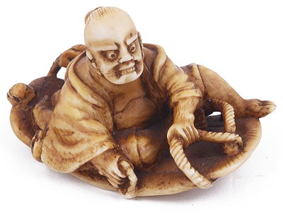 Lot 146 - ~STAINED IVORY NETSUKE OF A NIO ON A GIANT SANDAL