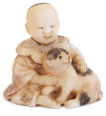 Lot 151 - ~STAINED WALRUS IVORY NETSUKE OF A BOY SEATED WITH A DOG