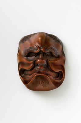 Lot 204 - A JAPANESE MASK NETSUKE OF A LARGE FROWNING OGRE