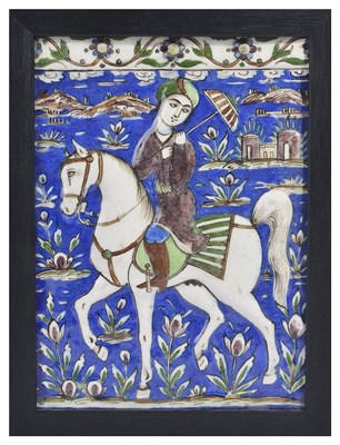 Lot 394 - A QAJAR RELIEF TILE DEPICTING A YOUNG PRINCE ON HORSEBACK
