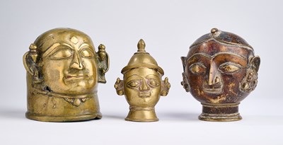 Lot 134 - TWO BRASS GAURI HEADS AND A SMALL SIVA MASK, MAHARASHTRA, INDIA, 19TH CENTURY